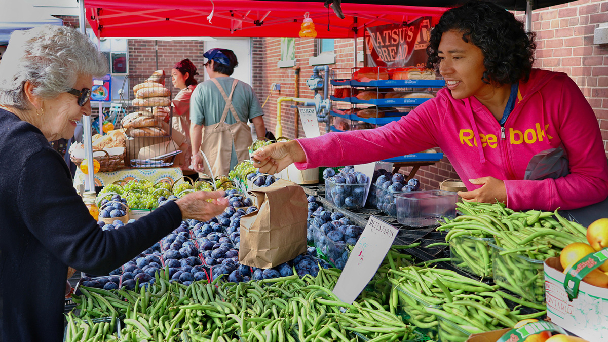 A shopper exchanged money with a vendor at Farmer's Market