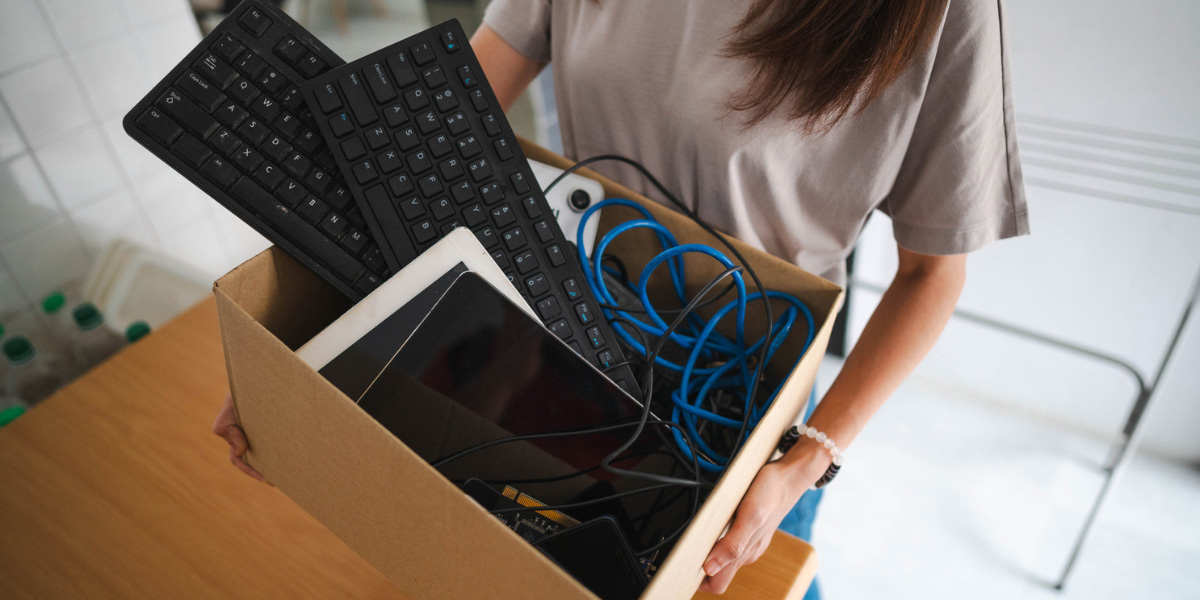A person holding a box of electronics to be recycled