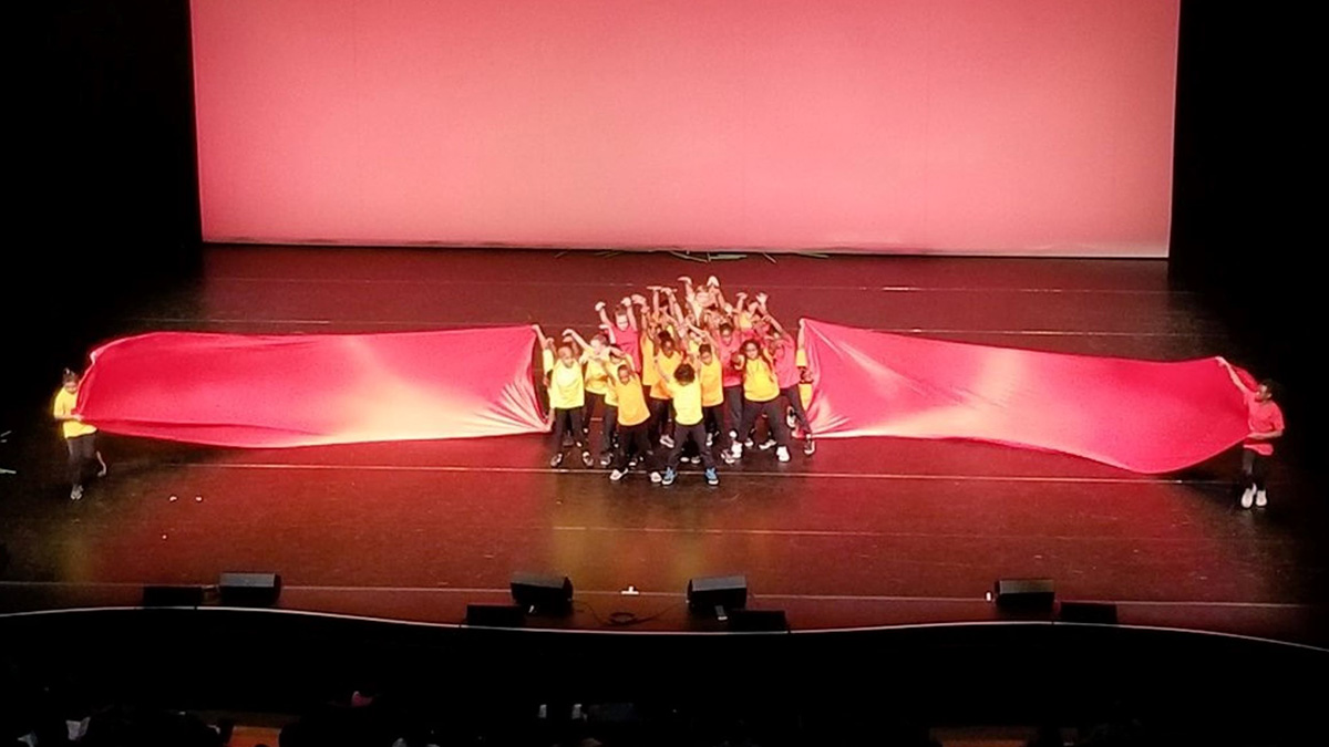 Students performing on stage with a red background