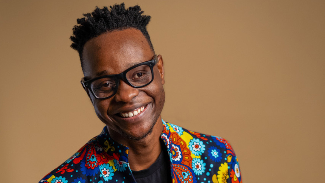 A comedian wearing glasses and colourful shirt