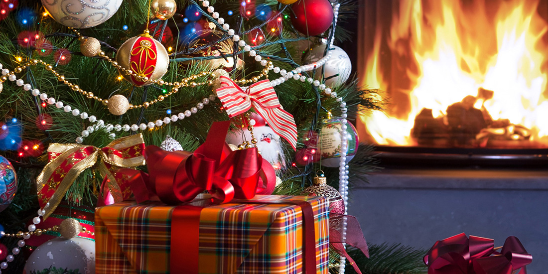Christmas tree with a fireplace in the background.