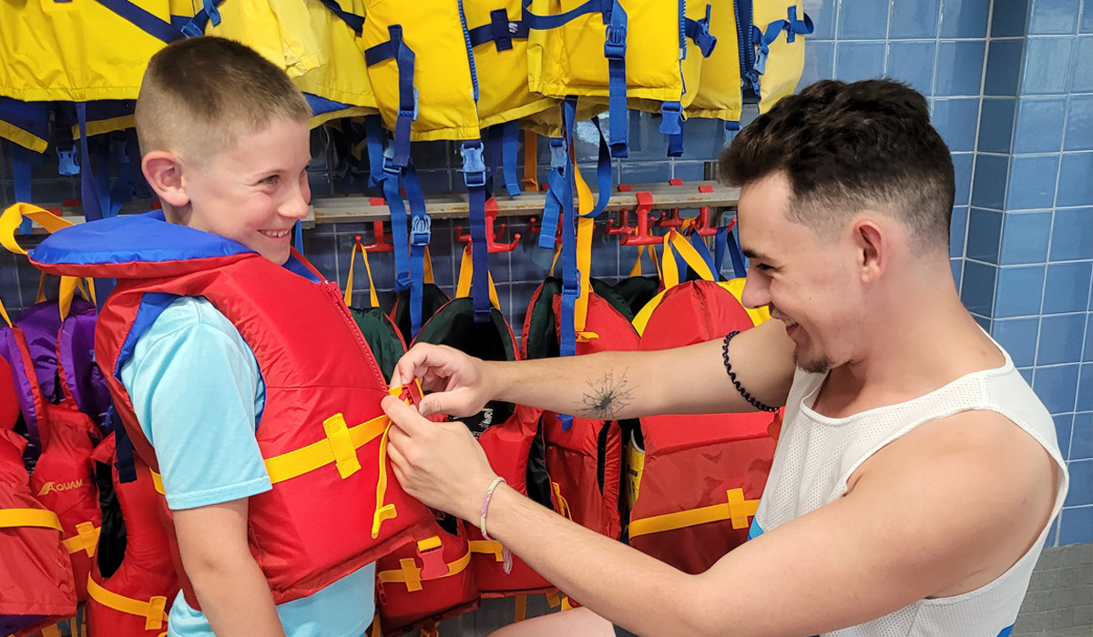 A lifeguard putting a life jacket on a child