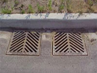 Two catch basins, or sewer grates next to a curb