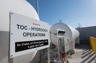 Two large white cylindrical tanks with a sign that reads TOC- Hydrogen Operations In Case of Emergency Call 1-800-461-4444