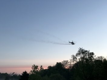 Aerial spray program with helicopter flying over trees
