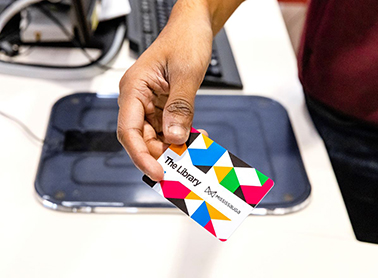 A person holds out a brightly coloured Mississauga Library Card for scanning