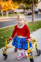 Disability photo of a cute little disabled girl walking with a s