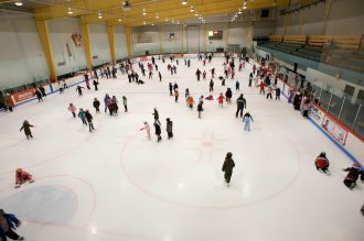 Many people skating at an indoor ice rink