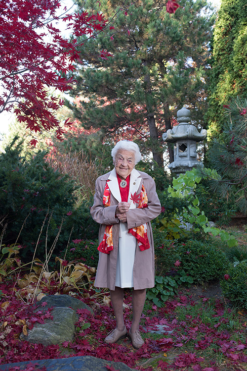 Hazel McCallion, former Mississauga Mayor, standing in the middle of a garden surrounded by fall foliage.