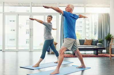 Image shows two seniors enjoying yoga and holding their pose