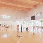 Adults and children taking part in soccer and basketball activities in a new gym.