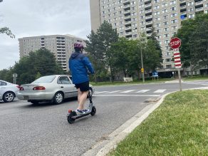 Person riding e-scooter on road with no bike lanes in Mississauga.