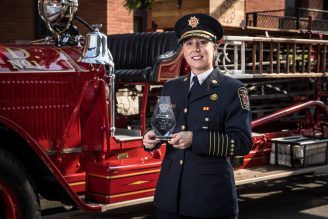 Photo of Fire Chief holding award in front of a fire truck.