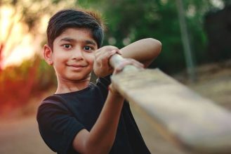 Young boy points a cricket bat at the camera