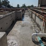 The concrete foundation of a building with large PVC pipes running through a trench.
