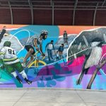 A colourful mural depicting athletic activities, like cycling and hockey.