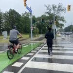 Cyclist and pedestrian crossing the intersection with a designated bike lane and bike signal installed.