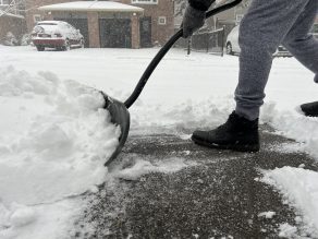Person shoveling snow on their driveway on a residential street