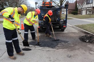 City crews filling a large pothole on local road