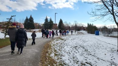 Students and parents walking on winter trail to school.