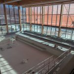 The therapeutic tank is tiled with benches and jets visible in a brightly lit space with many windows.