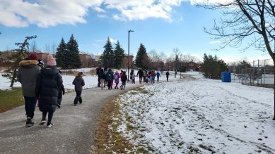 Students and parents walking on trail in the winter to school.