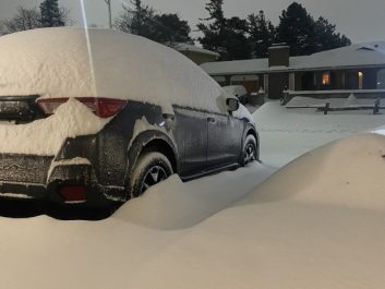 A car is snowed in to a driveway after a heavy snowfall.