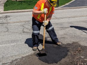 City staff filling a pothole on a street in Mississauga. 