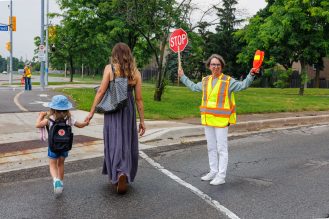 A parent and student walking with a crossing guard