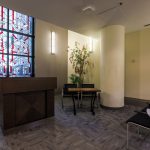 Podium in front of stained glass window with a plant.