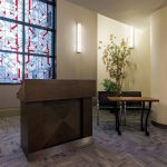 Podium in front of stained glass window with a plant.