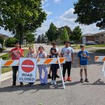 Photo: School children posing behind a road closed sign.