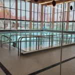 Indoor swimming pool surrounded by windows with view to outside