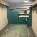 Long view of work shop with blue shelving and a green counter with mini sticks hanging from it