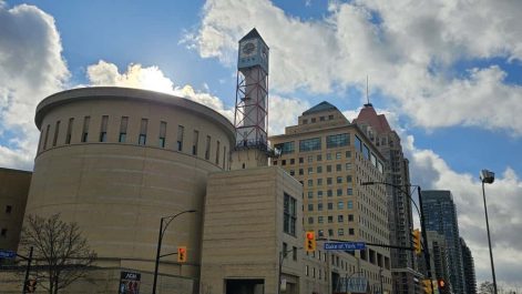 A building with the sun peaking out behind it.
