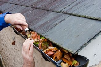 Person cleaning eavestrough from leaves.