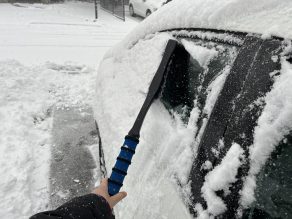 using brush to clean off snow from car