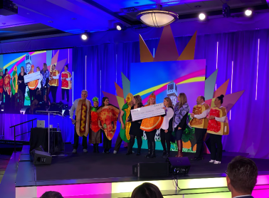 A group of people on stage with a big cheque