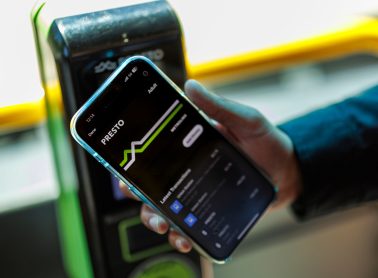 Photo of a hand tapping a PRESTO fare card on a card reader inside a MiWay bus.