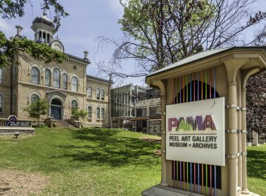 A outdoor image of a historical building, landscpaing and a sign out front