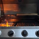 Close up of BBQ at home with fire and meat on the grill.