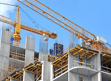 Construction site showing tall building under construction with yellow crane