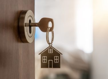 Key with house-shaped keychain inserted into a lock