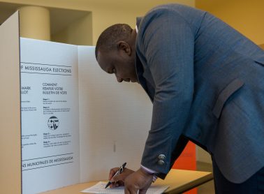 A person voting behind a privacy screen.