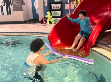 A City of Mississauga life guard helps a child safely use a water slide.
