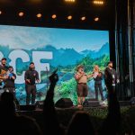 People on a stage with an image of mountains and trees behind them.