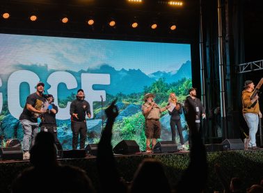 People on a stage with an image of mountains and trees behind them.