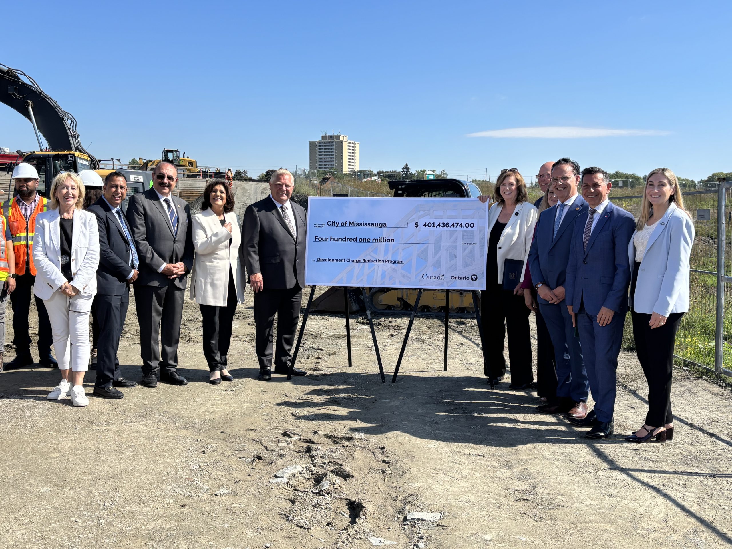 Group standing next to ceremonial cheque on a construction site