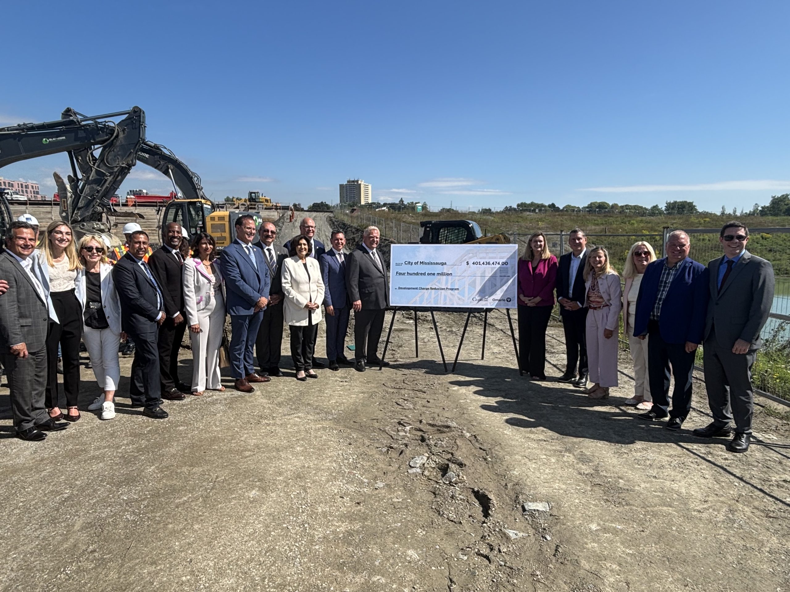 Group of people on construction site surrounding ceremonial cheque