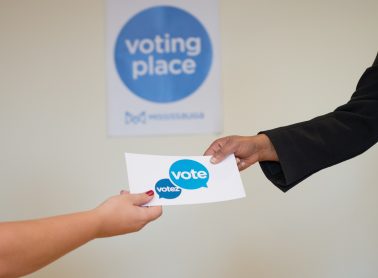 Two hands holding a vote card.
